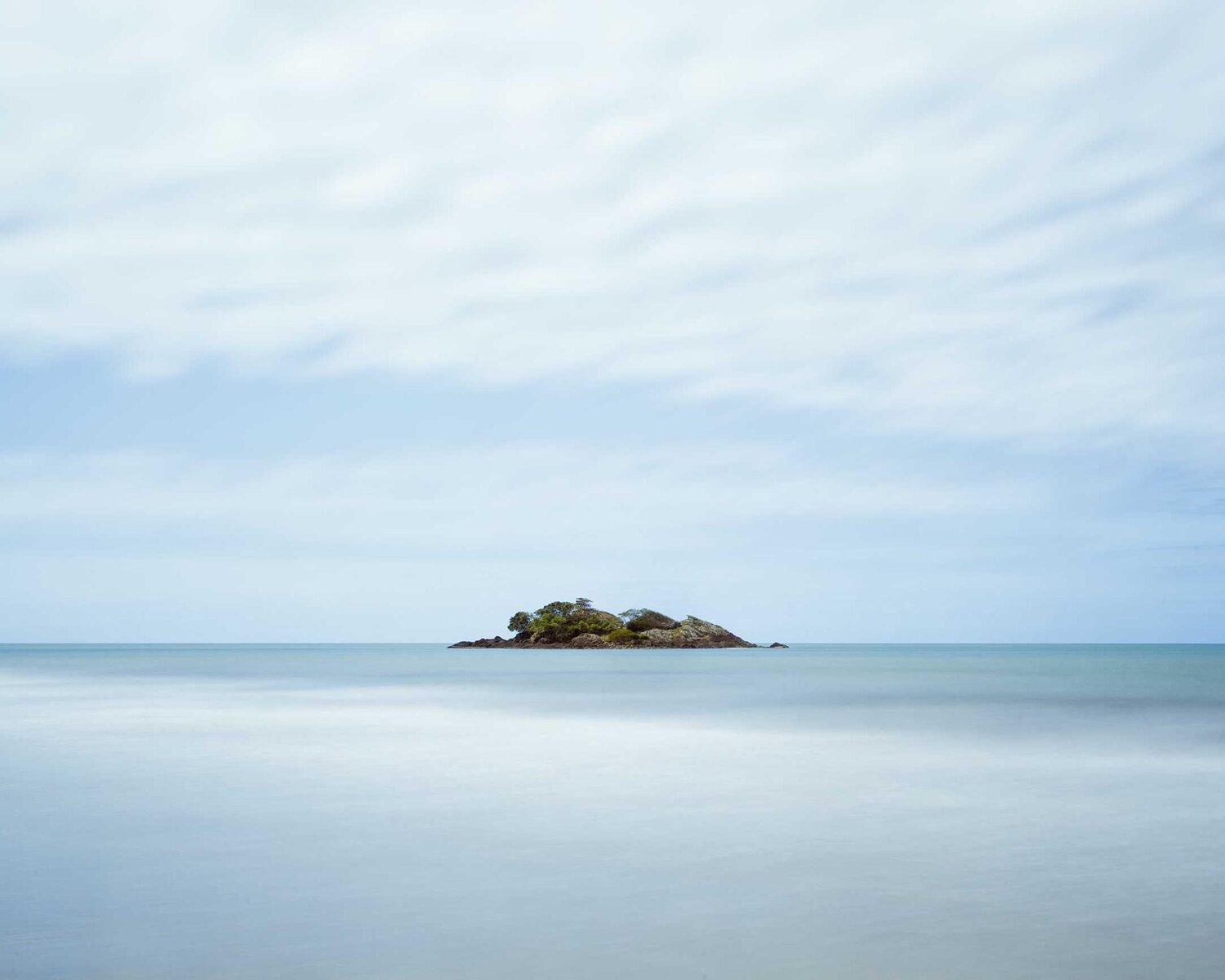 Small island on a calm, pale sea