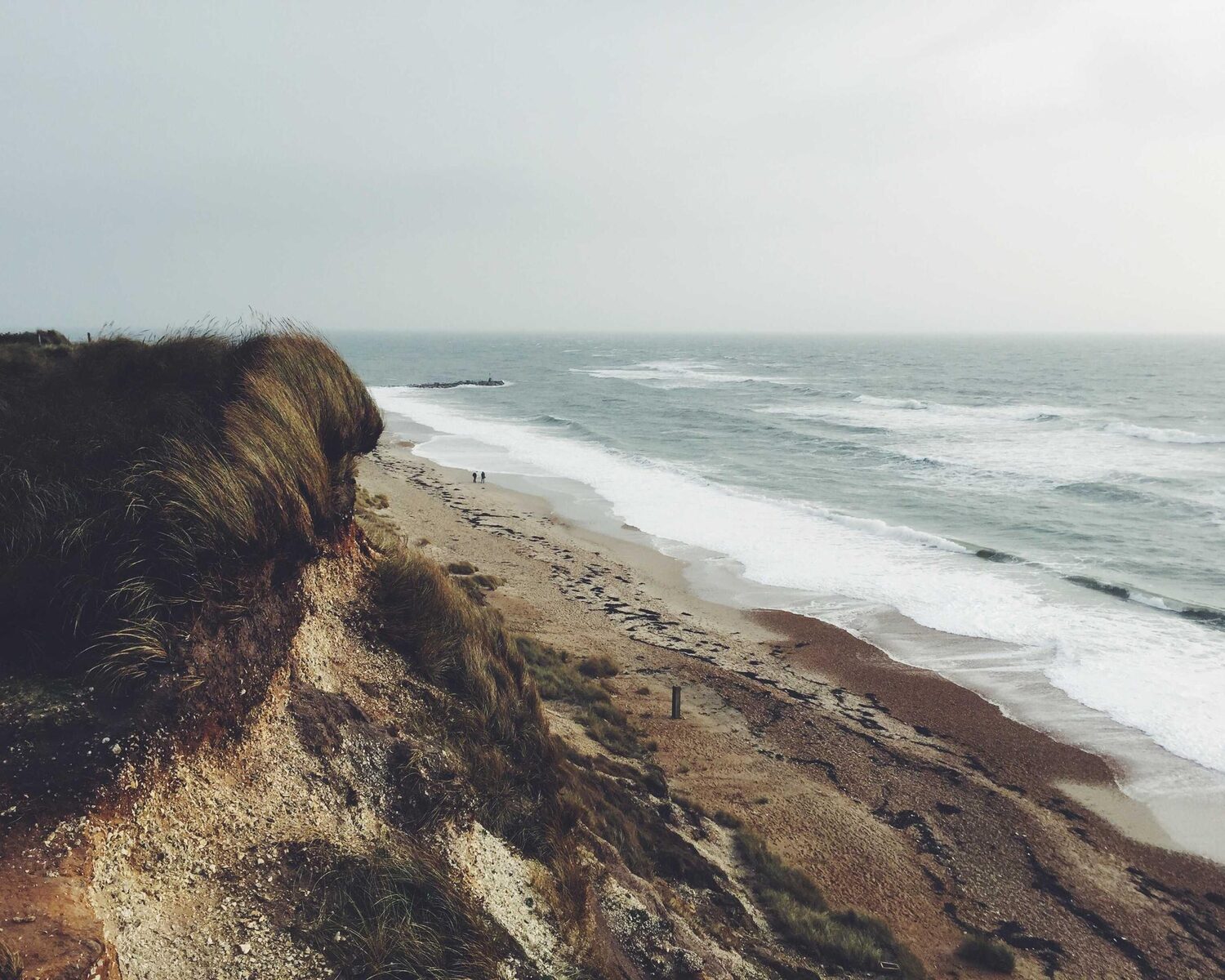 Sandy cliff above a long, empty beach