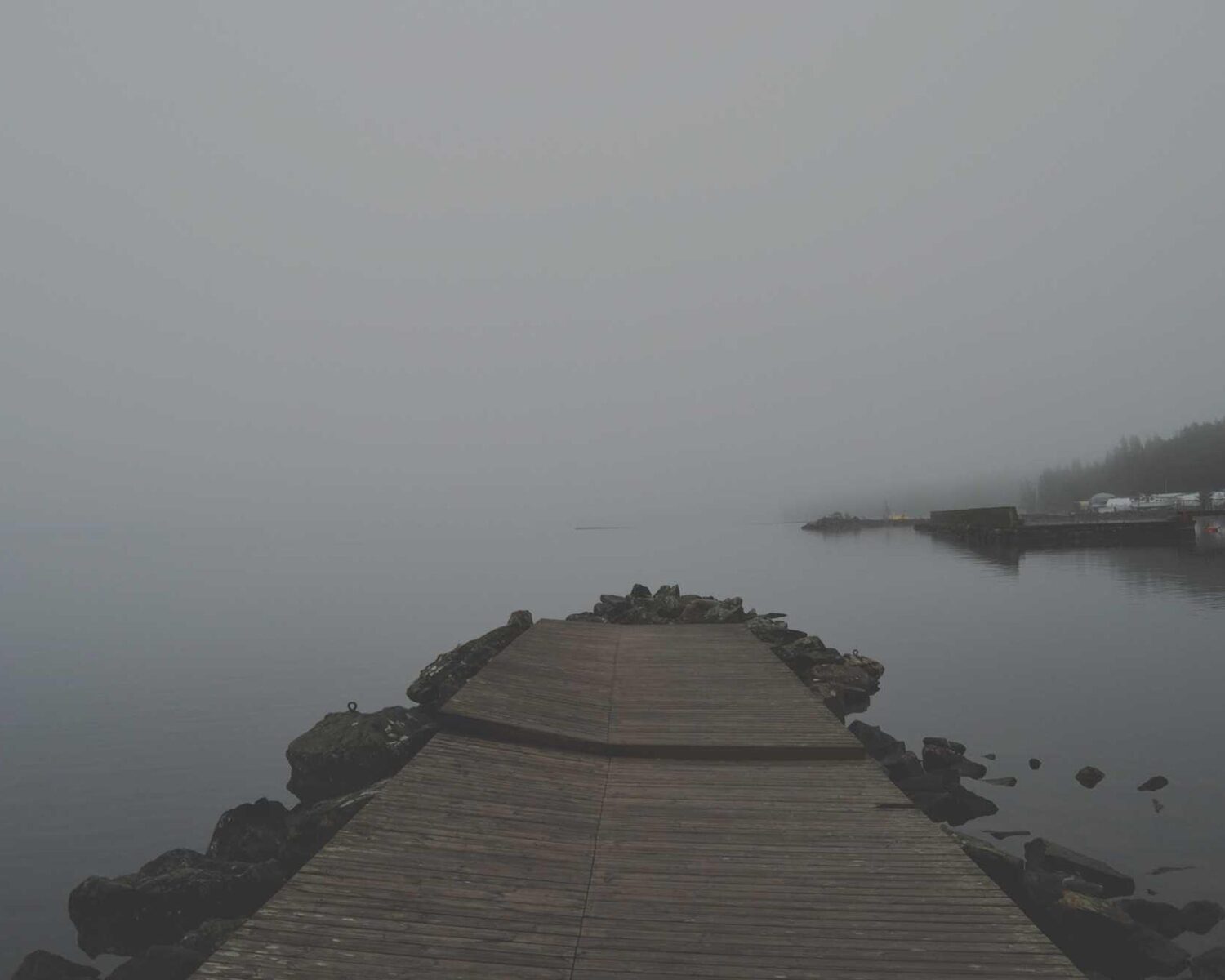 Stone jetty disappearing into grey fog