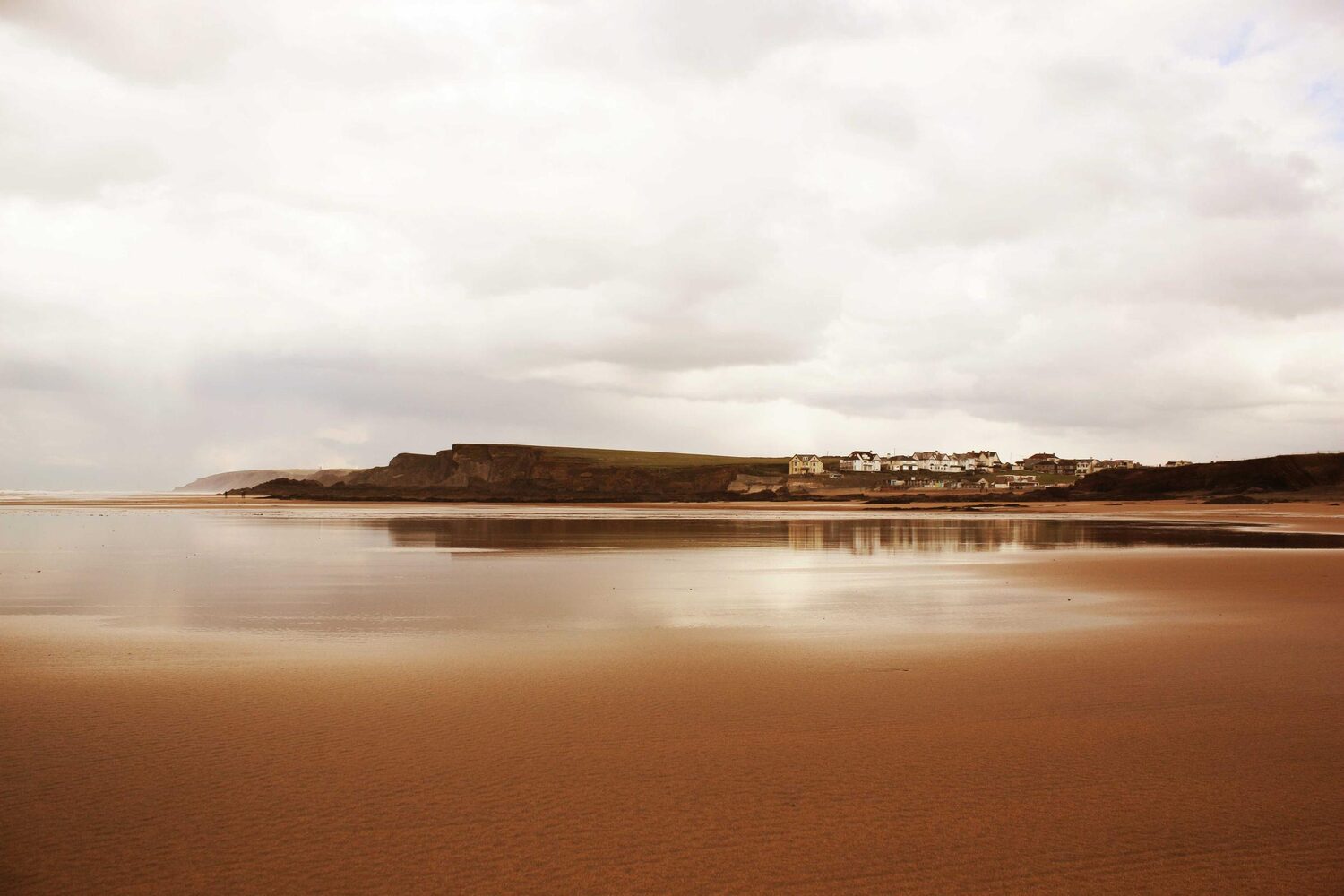 Wide tidal beach under a soft, cloudy sky
